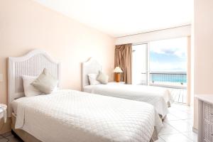 two beds in a white room with a view of the ocean at 2 bedrooms appartement with sea view indoor pool and furnished balcony at Lowlands in Lowlands