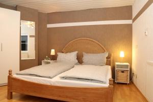 um quarto com uma cama de madeira com lençóis e almofadas brancos em Ferienwohnung Vogler em Herscheid