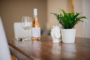 Adriatico Home[Mare-Fiera-Centro] في باري: طاولة خشبية مع زجاجة من النبيذ ونبتة