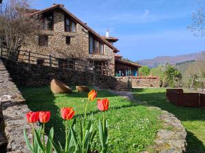 een stenen huis met rode tulpen ervoor bij Viviendas Rurales El Covaju in Cabezón de Liébana