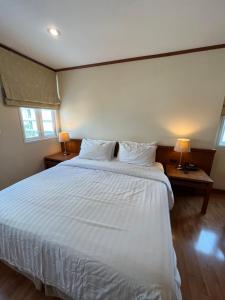 a bedroom with a large white bed with two lamps at Jhouse Thonglor in Klong Toi +6 photos