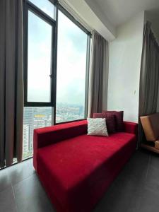 - un canapé rouge dans une chambre avec une grande fenêtre dans l'établissement Netflix Largest Studio @ Empire Damansara, à Petaling Jaya
