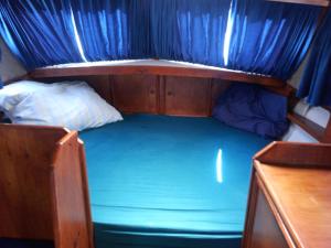 a small bed in a boat with a blue sheet at Ubytování na námořní jachtě in Veselí nad Moravou