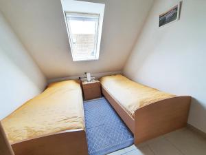 two beds in a small room with a window at Friesenhain Ferienwohnungen in Sankt Peter-Ording