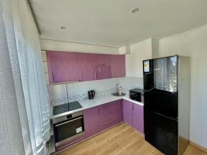 a kitchen with purple cabinets and a black refrigerator at Luks in Ventspils