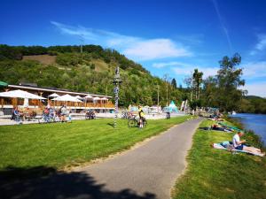 eine Gruppe von Menschen sitzt auf dem Gras in der Nähe eines Flusses in der Unterkunft Iglu Camp Fachbach in Fachbach