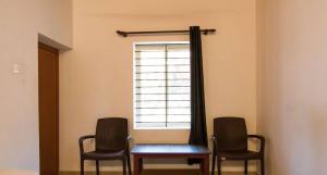 Habitación con mesa, 2 sillas y ventana en Westernghats Homestay en Madikeri