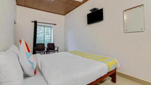 a white bedroom with a bed and a television at Westernghats Homestay in Madikeri