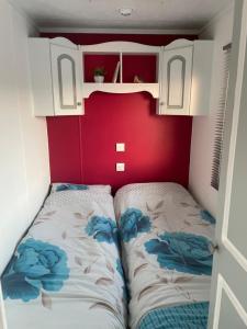 uma cama num pequeno quarto com uma parede vermelha em Farm stay property Pets and families welcome em Rossnowlagh