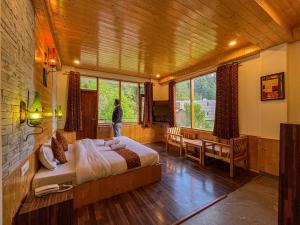 a man is standing in a bedroom with a bed at 17 Milestones Hotel -River Side in Manāli