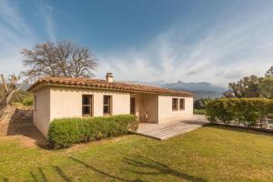 a small white house with a porch and a yard at Casa di Pruno in Figari