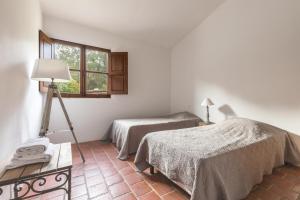 a room with two beds and a lamp and a window at Casa di Pruno in Figari