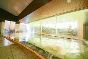 einen Pool in einem Gebäude mit Glaswand in der Unterkunft Ooedo Onsen Monogatari Ikaho in Shibukawa