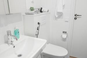biała łazienka z toaletą i umywalką w obiekcie Snowflake Suites IV w mieście Rovaniemi