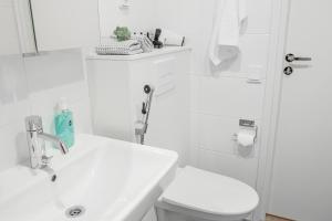 a white bathroom with a toilet and a sink at Snowflake Suites IV in Rovaniemi