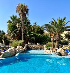 a swimming pool in a resort with palm trees at Apartamentos Moguima in Roquetas de Mar