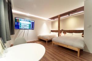 a bedroom with two beds and a tv on the wall at THE LOBS, RUSUTSU in Kimobetsu