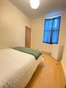 a bedroom with a bed and a window with blue curtains at Seven Sister's rooms in London