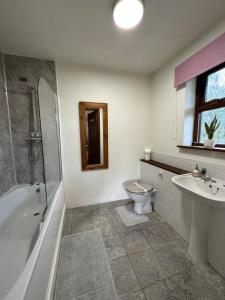 a bathroom with a tub and a toilet and a sink at Barnfields Retreat in Little Clacton
