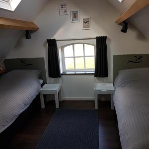 um quarto com 2 camas e uma janela em De Oude Koeienstal em Schimmert