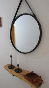 a mirror on a wall with two candles on a shelf at El Rincón de Alejandro in Arroyo Frio