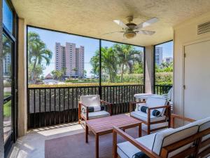 a screened porch with chairs and a table and a ceiling fan at Seaview #110 - Just Steps From 1 of 4 Public Beach Access Points in Marco Island