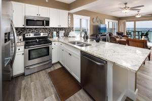 uma cozinha com armários brancos e electrodomésticos de aço inoxidável em Emerald Twrs West 4000 by Brooks and Shorey Resorts condo em Fort Walton Beach
