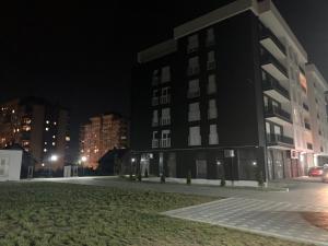 a large black building at night with buildings at Cozy Apartment Prishtina in Pristina