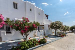 a white building with pink flowers and trees at Irene's Residence in Mikonos