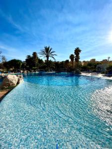 a large swimming pool with blue water at Apartamentos Moguima in Roquetas de Mar