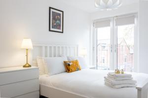 a white bedroom with a white bed and a window at The Chorlton in Manchester