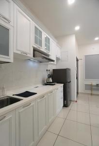 eine Küche mit weißen Schränken und einem schwarzen Kühlschrank in der Unterkunft D’Summit residences, Setia tropika , Johor Bahru in Johor Bahru