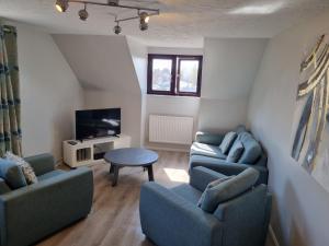 sala de estar con 2 sofás azules y TV en Spacious Family Friendly Apartment- 100m from beach with Seaviews! en Hunstanton