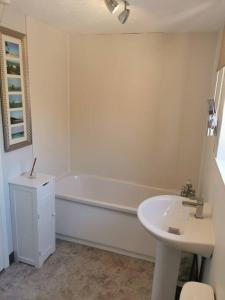 Baño blanco con bañera y lavamanos en Spacious Family Friendly Apartment- 100m from beach with Seaviews! en Hunstanton