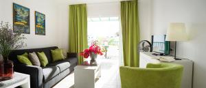un soggiorno con tende verdi e divano di Apartamentos El Guarapo a Costa Teguise