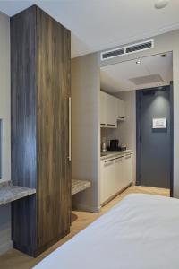 a bedroom with a large wooden cabinet next to a kitchen at Breathe Hotel Leiden in Leiden