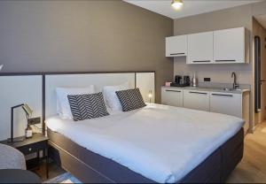 a bedroom with a large bed and a kitchen at Breathe Hotel Leiden in Leiden