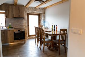 a kitchen with a wooden table with chairs and a counter at Kamena Kuća Vegar in Ljubuški