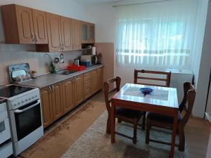 a kitchen with wooden cabinets and a table with chairs at Kuca za odmor Una-Mia in Kulen Vakuf