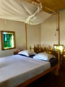 a bedroom with a bed with a canopy at Corto Novo Maison d'hôtes-Camping in Nosy Be