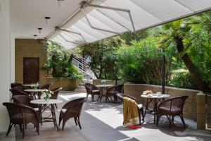 eine Terrasse mit Tischen und Stühlen unter einem weißen Schirm in der Unterkunft Hotel Maddalena in Riccione