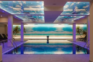 a large swimming pool in a building with a aquarium at Astrea Deluxe in Hisarya