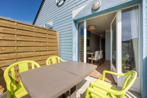 a patio with a table and yellow chairs on a deck at Némo - Appartement avec Terrasse in Courseulles-sur-Mer