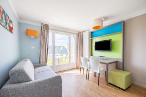 ein Wohnzimmer mit einer Couch, einem Tisch und einem Fernseher in der Unterkunft Némo - Appartement avec Terrasse in Courseulles-sur-Mer