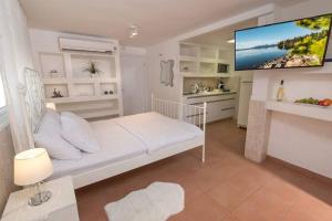 a living room with a white bed and a tv at נווה שחר- צימר משפחתי מקסים עם ג'קוזי פרטי ובריכה ליד הכנרת in Poriyya Illit