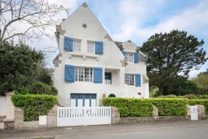 una casa blanca con ventanas azules y una valla blanca en Échappée familiale à deux pas de la plage, en Le Pouliguen