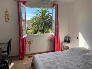 a bedroom with a bed and a window with a palm tree at Magnifiques chambres dans 100m2 au calme Saint Cyprien Plage in Saint-Cyprien