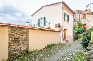ein weißes Haus mit einer Steinmauer und einem Gehweg in der Unterkunft Comfy & Roomy Apt - View on the Ligurian Hills! in Vezzano Ligure