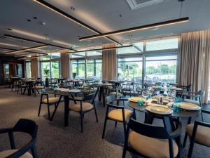 a restaurant with tables and chairs and large windows at Hotel Villa Rosetta in Savudrija