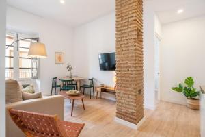 sala de estar con sofá y pilar de ladrillo en Apartamentos Luna Suites Palacio Dorita, en Granada